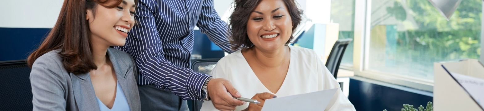 two-asian-female-one-male-colleagues-discussing-document-together-office